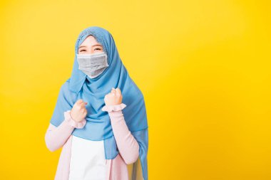 Müslüman Arap, duvak takan güzel kadın koruyucu yüz maskesi takıyor. Koronavirüs karantina altına alınıyor. Hastalıktan kurtulduktan sonra sevinçten havalara uçuyor.