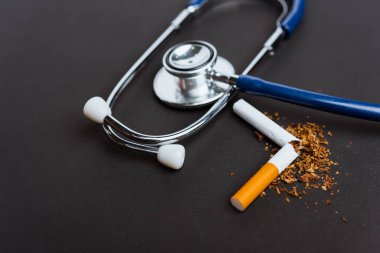 31 Mayıs Dünya Sigara Yok Günü, Sigara yok, kırık sigara veya tütün yığınının kapanışı ve fotokopi alanı olan siyah arka planda doktor steteskobu ve akciğer sağlığı konsepti