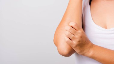 Asyalı güzel bir kadın elini kaşıyarak kaşınıyor beyaz arka planda fotokopi alanı, sağlık ve sağlık hizmetleri konsepti ile kollarını kaşındırıyor.