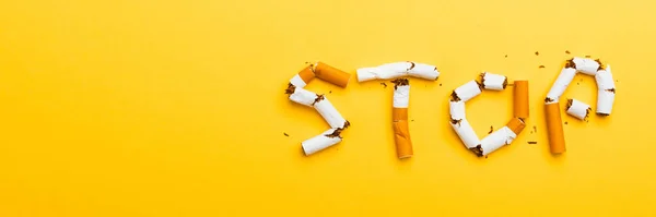 31 May of World No Tobacco Day, no smoking close up word STOP spelled text of the pile cigarette or tobacco on yellow background with banner copy space, and Warning lung health concept
