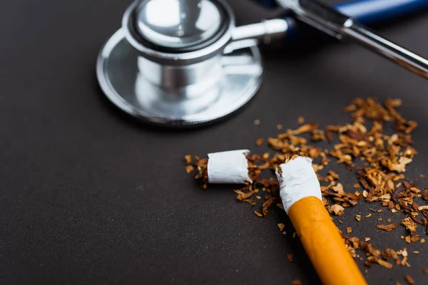 31 May of World No Tobacco Day, no smoking, close up of broken pile cigarette or tobacco and doctor stethoscope on black background with copy space, and Warning lung health concept
