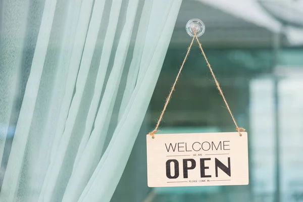 Close up of WELCOME WE ARE OPEN PLEASE COME IN notice sign wood board label hanging through glass door front shop, Business open back to new normal after coronavirus disease concept — Stock Image Close Welcome Open Please Come Notice Sign Wood Board Label Stock Image