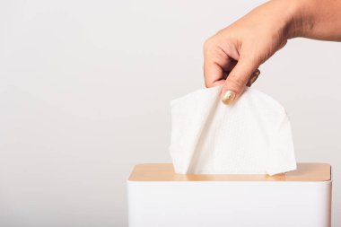 Genç kadın gribi. Beyaz mendiller için beyaz bir kutudan beyaz yüz dokusu alıyor. Stüdyo resmi beyaz arka planda izole edilmiş, sağlık sigortası konsepti.
