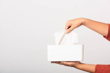 Genç kadın gribi. Beyaz mendiller için beyaz bir kutudan beyaz yüz dokusu alıyor. Stüdyo resmi beyaz arka planda izole edilmiş, sağlık sigortası konsepti.