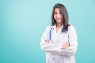 Asyalı doktor, mutlu, üniformalı, kolları bağlı genç bir kadın mavi arka planda steteskopla gülümsüyor ve sağlık personeli konsepti için fotokopi alanı yaratıyor.