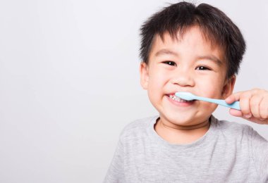 Kapalı Asyalı yüzü, küçük çocuk eli diş fırçasını tutuyor beyaz arka planda fotokopi alanı ve sağlık hizmeti ile dişlerimi fırçalıyor.