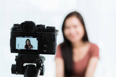 Evden çalışıyorum. Gülümseyen Asyalı genç güzel kadın blogcu profesyonel dijital teknoloji ekipmanıyla canlı yayında video konferansını canlı olarak kaydediyor.