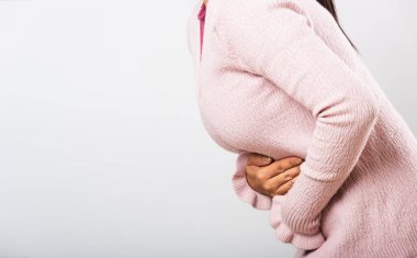 Asyalı bir kadın hasta, karın ağrısı var, karın ağrısı, karın ağrısı, karın ağrısı sorunu, kabızlık ya da bağırsak sorunu, beyaz arka planda izole edilmiş stüdyo çekimi.