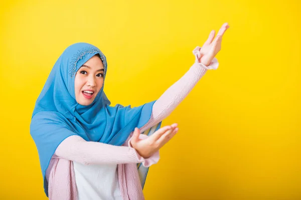 アジア系イスラム教徒アラブ人 幸せな美しい若い女性の肖像イスラム教の宗教的な服ベールヒジャーブ面白い笑顔彼女は抱擁のための腕を開くか アイテムを拾うために手を上げます孤立黄色の上から何かを受け取る — ストック写真