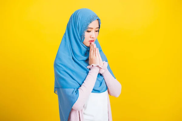 Asian Muslim Arab, Portrait of happy beautiful young woman religious wearing veil hijab she henna decorated hands praying to Allah God, isolated on yellow background, Eid Mubarak and soul fasting