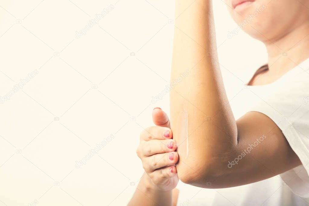 Closeup young Asian woman applies lotion cream on her elbow, studio shot isolated on white background, Healthcare medical and hygiene skin body care concept