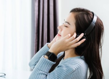 Evde çalışmak, Asyalı genç iş kadını kendini rahat hisseder. Kulaklıklı kulaklıkla müzik dinler. Bilgisayarda, karantinada, Coronavirüs hastalığında ya da merkez ofiste COVID-19 'da.