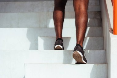 Close up athlete shoes of legs young sport runner black man step running up to climbing stairs doing training cardio sport workout at the outdoor street, healthy exercise before workout concept clipart
