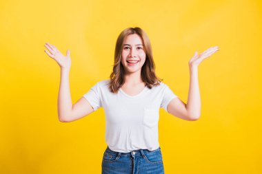 Asya Tayland mutlu portresi güzel şirin genç kadın tişörtü giyiyor kazanan ve şaşıran çığlığı atan ağzı açık, eller açık, stüdyo çekimleri izole edilmiş sarı arka plan ve fotokopi alanı