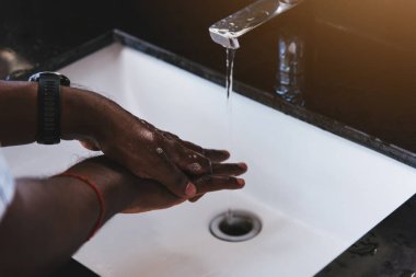 Siyah adamın ellerini yıkamak lavaboya sabun ve suyla ovmak salgın koronavirüsünün virüs yaymasını önlemek için, COVID-19 konseptini karantina temizliği için hijyen.