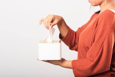 Genç kadın gribi. Beyaz mendiller için beyaz bir kutudan beyaz yüz dokusu alıyor. Stüdyo resmi beyaz arka planda izole edilmiş, sağlık sigortası konsepti.