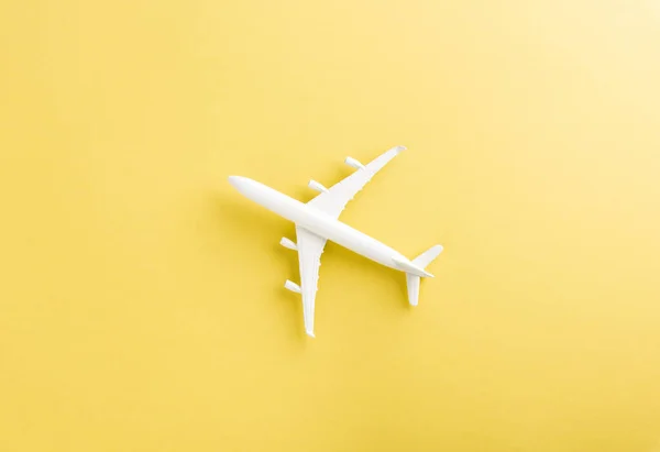 World Tourism Day, Top view flat lay of minimal toy model plane, airplane with copy space, studio shot isolated on a yellow background, accessory flight holiday concept