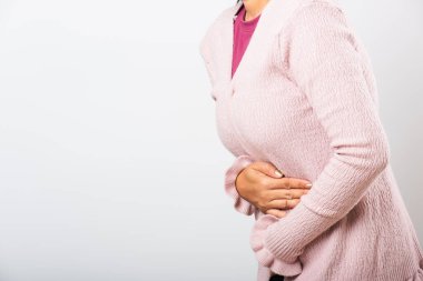 Asyalı bir kadın hasta, karın ağrısı var, karın ağrısı, karın ağrısı, karın ağrısı sorunu, kabızlık ya da bağırsak sorunu, beyaz arka planda izole edilmiş stüdyo çekimi.