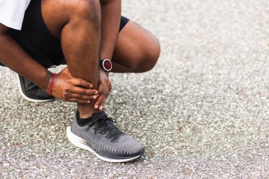 Kapatın Asyalı genç spor koşucusu. Siyah adam kol eklemli el takıyor. Ayak bileği burkulduğu için bacak ağrısı çekiyor.