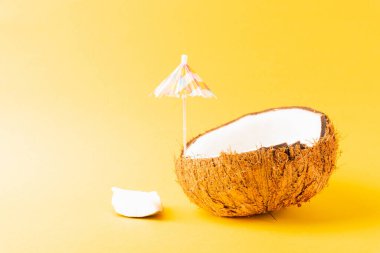 Mutlu hindistan cevizi günü konsepti, taze hindistan cevizi ve güneş şemsiyesi, stüdyo çekimi sarı arka planda izole edilmiş, plaj tropikal meyve yaz tatili