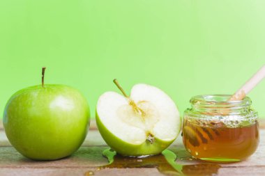 Yahudi bayramı konsepti, Apple Rosh Hashanah tatlı günü, fotoğrafta kavanozda bal var ve yeşil elmaların üzerine bal dökülüyor.