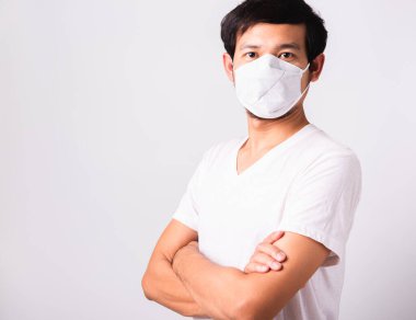 Coronavirus 'a karşı cerrahi hijyenik koruyucu yüz maskesi takan yakışıklı Asyalı adam çapraz kol duruşu, izole edilmiş beyaz arka plan, COVID-19 tıbbi konsept.