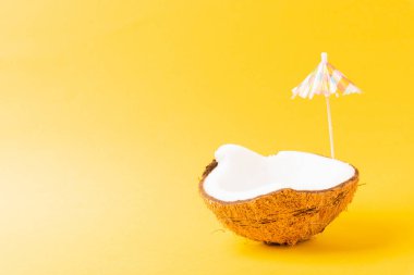 Mutlu hindistan cevizi günü konsepti, taze hindistan cevizi ve güneş şemsiyesi, stüdyo çekimi sarı arka planda izole edilmiş, plaj tropikal meyve yaz tatili
