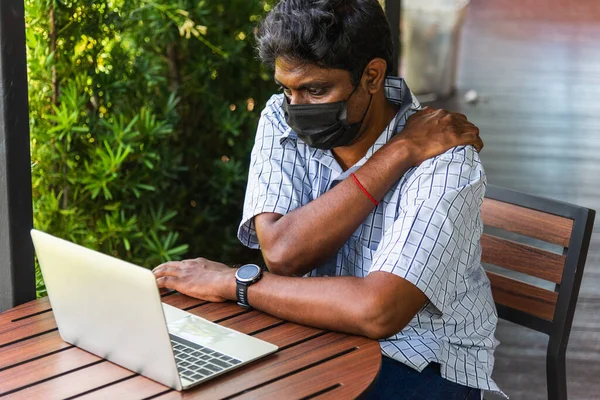 Closeup back the Asian black man use hand holding chiropractor shoulder really bad neck pain from using laptop computer he working long time, Injury office syndrome by occupational disease concept