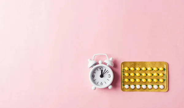 World sexual health or Aids day, Top view flat lay medicine birth control, alarm clock and contraceptive pills, studio shot isolated on a pink background, Safe sex and reproductive health concept