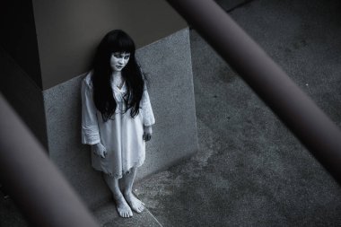 Kadın hayalet korkusu binanın altında duruyor yukarı bakıyor, cadılar bayramı konseptine bakıyor.