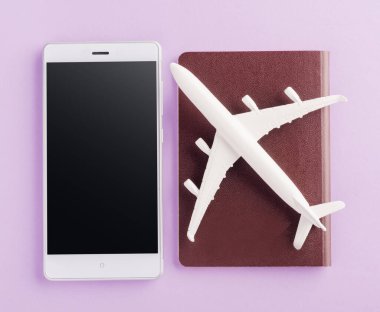 Dünya Turizm Günü, Minimum oyuncak model uçak, Pasaportlu uçak ve cep telefonlu boş ekran, Mor bir arka planda izole edilmiş stüdyo çekimi, aksesuar uçuş tatil konsepti