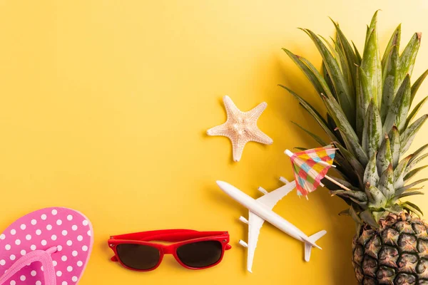 Celebrate Summer Pineapple Day Concept, Top view flat lay of funny pineapple, sunglasses, model plane, starfish and clock alarm isolated on yellow background, Holiday summertime in tropical