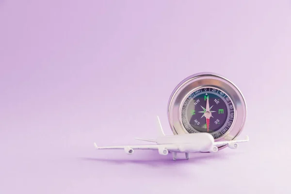 World Tourism Day, minimal toy model plane and compass, studio shot isolated on a purple background with copy space for text, holiday travel concept