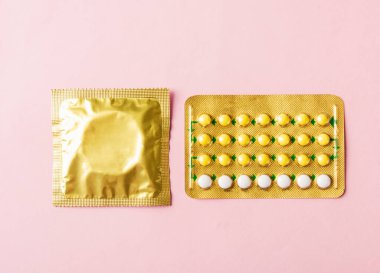 Dünya seks sağlığı ya da AIDS günü, prezervatif paketi ve doğum kontrol hapları hormonal doğum kontrol hapları, pembe arka planda izole edilmiş stüdyo çekimi, güvenli seks ve üreme sağlığı konsepti.