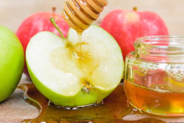 Yahudi bayramı, Elma Rosh Hashanah, fotoğraf kavanozda bal var ve ahşap arka planda yeşil elmalara bal dökülüyor.