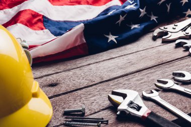 ABD İşçi Bayramı konsepti, ahşap masa üzerinde Amerikan bayrağı olan çeşitli İngiliz anahtarı. Eylül 'ün ilk pazartesi günü, işçi hareketinin kurulması ve Amerikan işçilerinin sosyal hizmetlerine adanması.