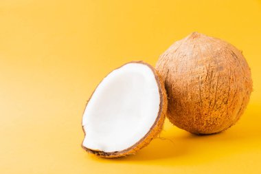 Mutlu hindistan cevizi günü konsepti, yarım hindistan cevizli taze hindistan cevizi, sarı arka planda izole edilmiş stüdyo çekimi.