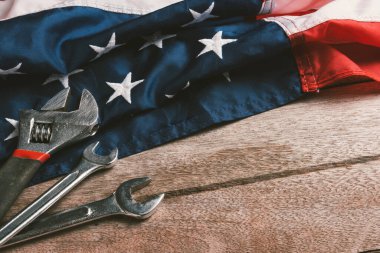 ABD İşçi Bayramı konsepti, ahşap masa üzerinde Amerikan bayrağı olan çeşitli İngiliz anahtarı. Eylül 'ün ilk pazartesi günü, işçi hareketinin kurulması ve Amerikan işçilerinin sosyal hizmetlerine adanması.