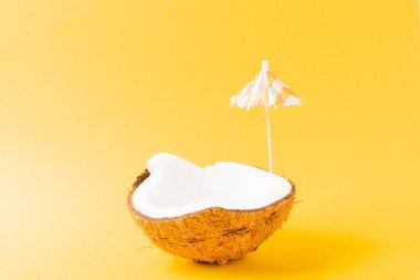 Mutlu hindistan cevizi günü konsepti, taze hindistan cevizi ve güneş şemsiyesi, stüdyo çekimi sarı arka planda izole edilmiş, plaj tropikal meyve yaz tatili