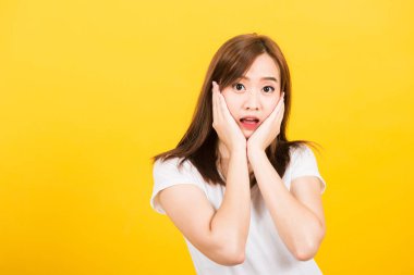 Asyalı mutlu bir portre güzel, genç bir kız heyacanlı bir şekilde ayakta duruyor. Ağızları açık, el hareketleriyle hareket eden, izole edilmiş kameralara bakan, fotokopi çekilen sarı arka plan.