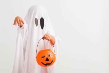 Komik Cadılar Bayramı Çocuğu kavramı, beyaz kostümlü küçük şirin çocuk Cadılar Bayramı hayaleti korkunç elinde turuncu kabak hayaleti, beyaz arka planda tek başına çekilmiş bir stüdyo resmi.