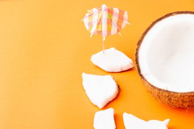 Mutlu hindistan cevizi günü konsepti, taze hindistan cevizi dilimleri ve güneş şemsiyesi, stüdyo çekimi turuncu arka planda, plaj tropikal meyve yaz tatili