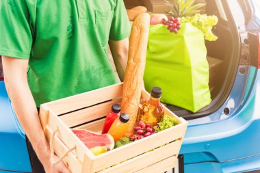 Asyalı teslimatçı market hazırlama servisi arka vagondaki ahşap sepetle taze sebze ve meyve vererek kadın müşteriyi pandemik koronavirüsten sonra evine yolluyor.