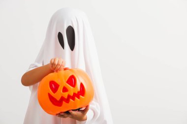Komik Cadılar Bayramı Çocuğu kavramı, beyaz kostümlü küçük şirin çocuk Cadılar Bayramı hayaleti korkunç elinde turuncu kabak hayaleti, beyaz arka planda tek başına çekilmiş bir stüdyo resmi.