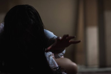 Kanlı kız zombi. Kanlı Asyalı kadın hayalet. Karanlık evdeki korkunç korku tüyler ürpertici sürünme yavaş yavaş yayılıyor. Saç kaplaması kameraya bakıyor, Cadılar Bayramı festivali konsepti.