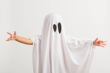 Komik cadılar bayramı çocuğu kavramı, beyaz kostümlü şirin çocuk cadılar bayramı hayaleti korkunç, stüdyo resmi beyaz arka planda izole edilmiş.