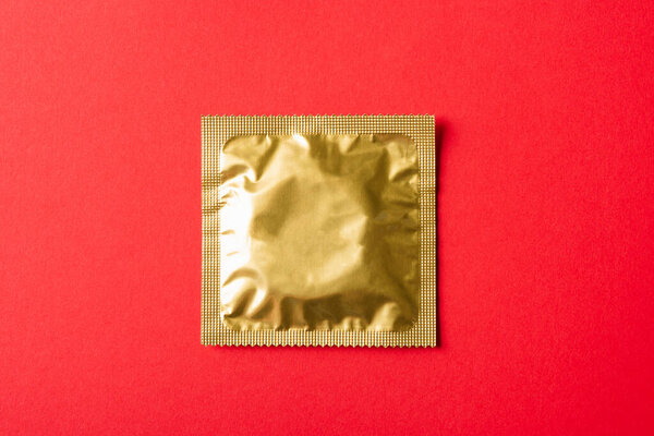 World sexual health or Aids day, Top view flat lay condom in wrapper pack, studio shot isolated on a red background, Safe sex and reproductive health concept