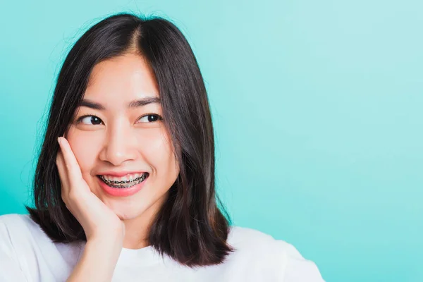 アジアの10代の美しい若い女性の笑顔の肖像彼女は手で彼女の顔に触れる笑って歯の歯のブレースを持っています 青の背景に隔離されたスタジオショット 医学と歯科の概念 — ストック写真