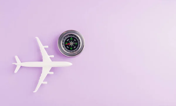 World Tourism Day, minimal toy model plane and compass, studio shot isolated on a purple background with copy space for text, holiday travel concept