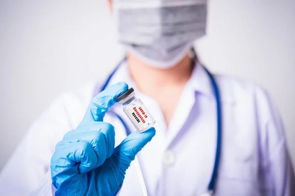 女医生或穿着制服 戴口罩 在实验室进行防护的科学家用手指头托住瓶装疫苗瓶 瓶装疫苗上有 Coronavirus Vaccine 即Covid — 图库照片